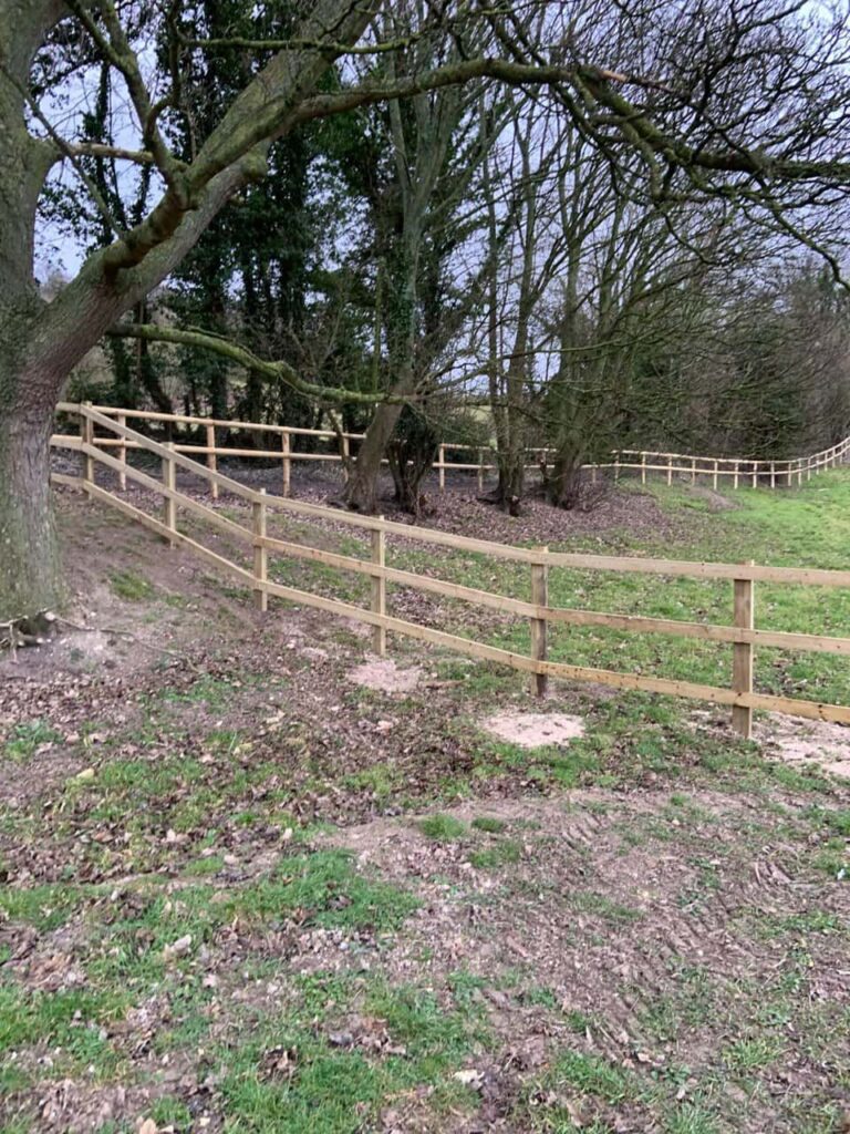 This is a photo of post and rail fencing installed around the perimeter of sloped garden by Fast Fix Fencing.