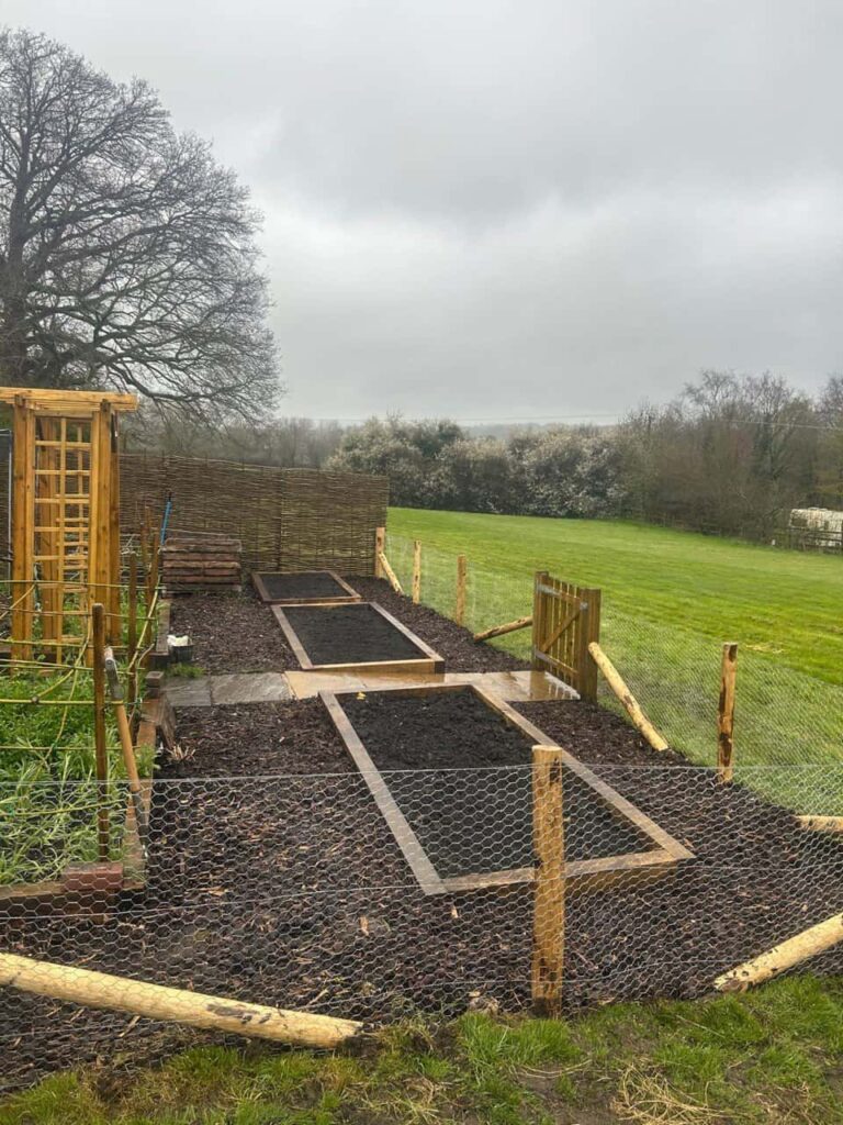 This is a photo of a stock fence installed around the perimeter of a large vegetable garden, there is also a wooden gate as well. Installation carried out by Fast Fix Fencing